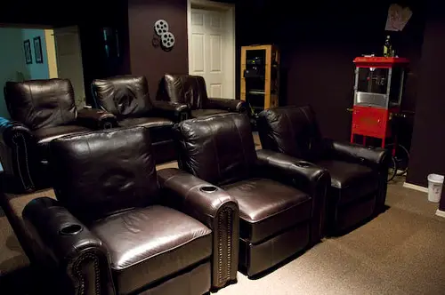 A home theater room with surround speakers positioned around the seating