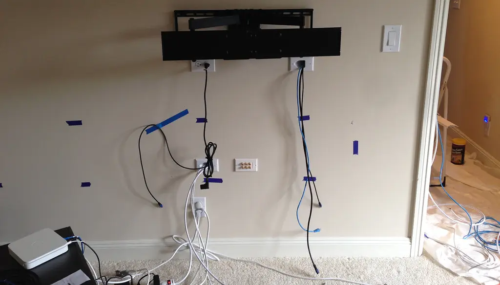 A center channel speaker mounted directly below a television, aligned with the screen center and aimed at the seating area